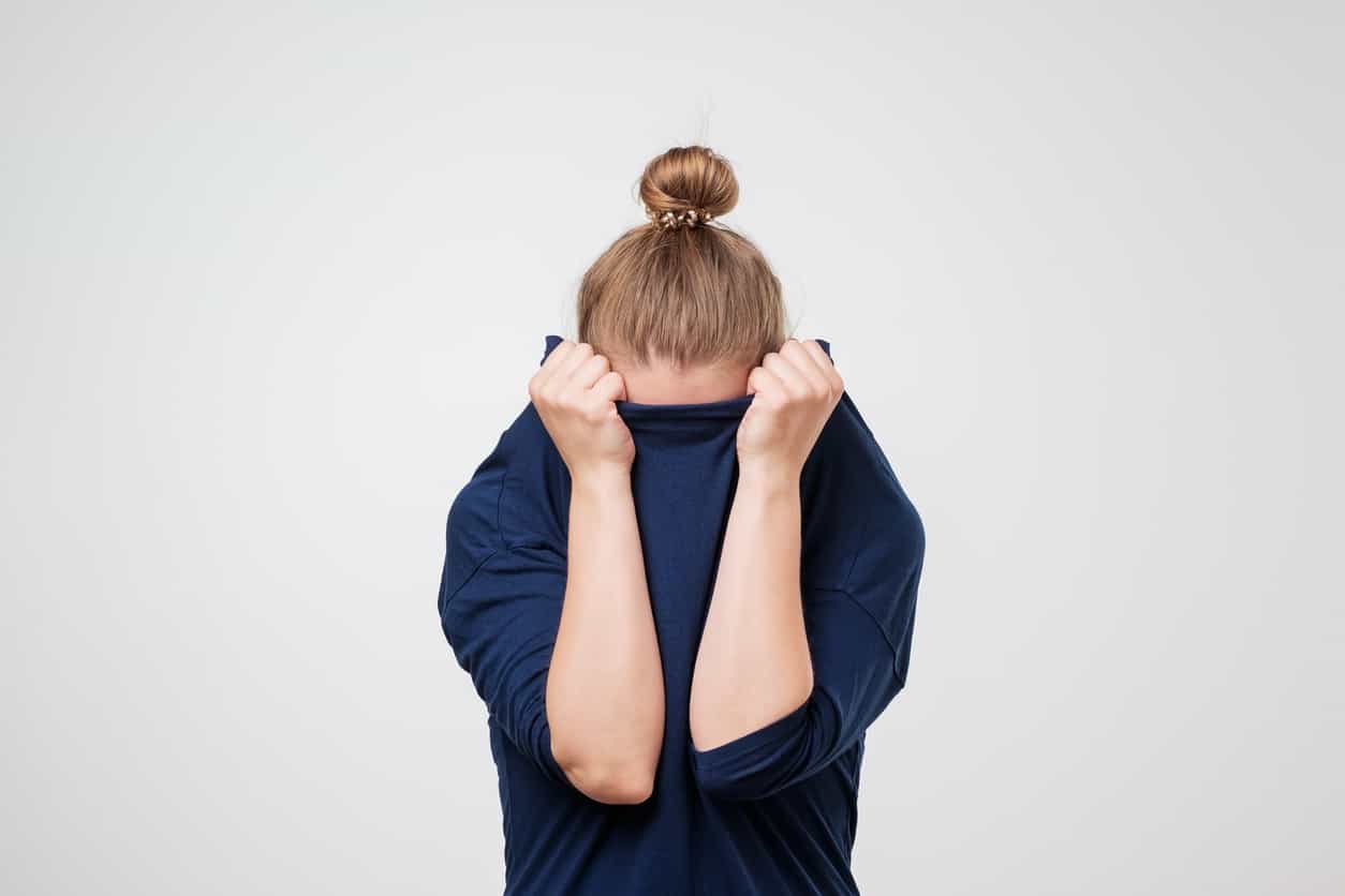 frustrated girl pulling her shirt collar up over her face